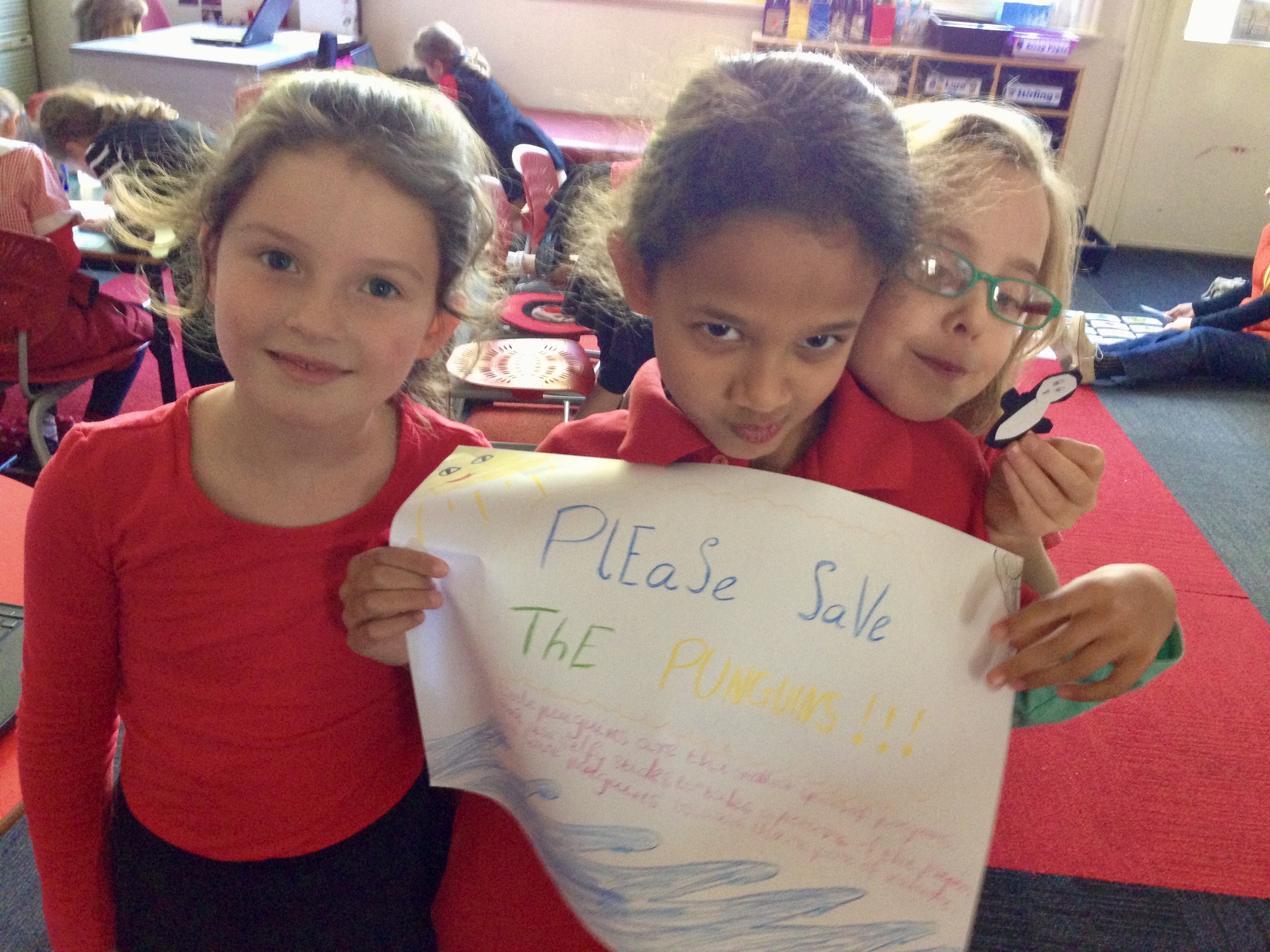 3 children holding a poster that says please save the penguins