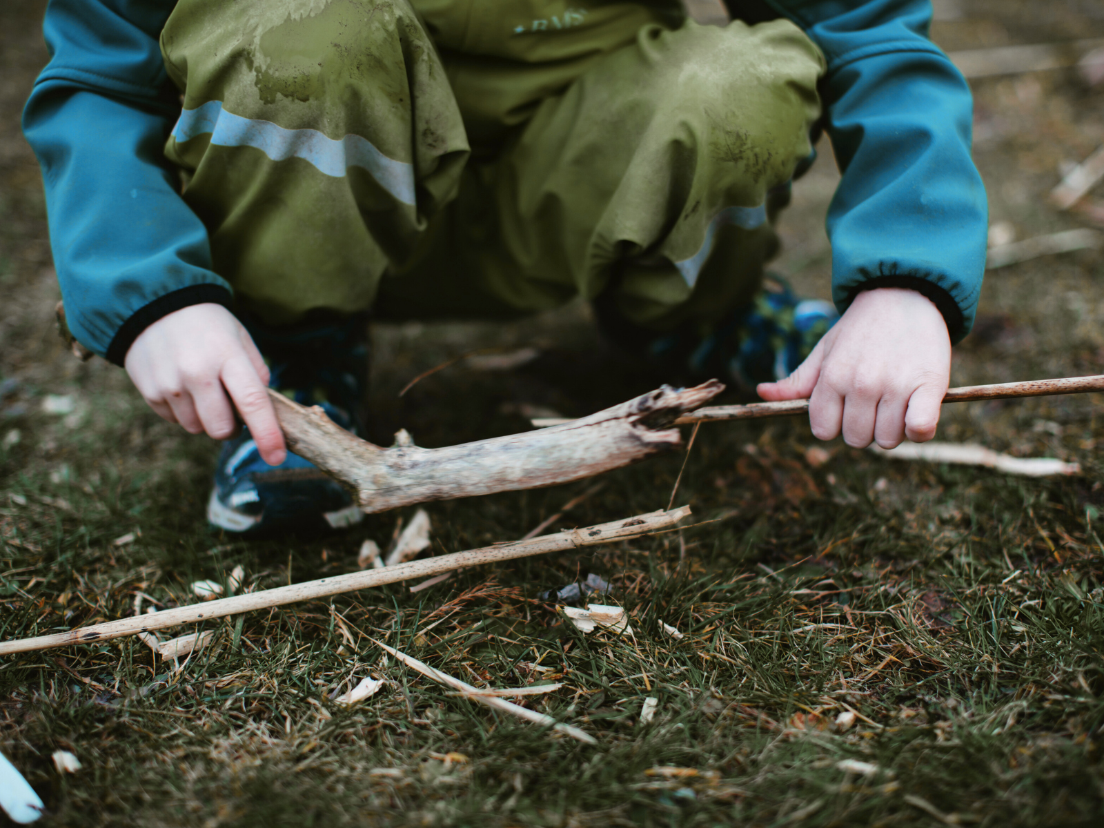 Kid crouching down holding a stick
